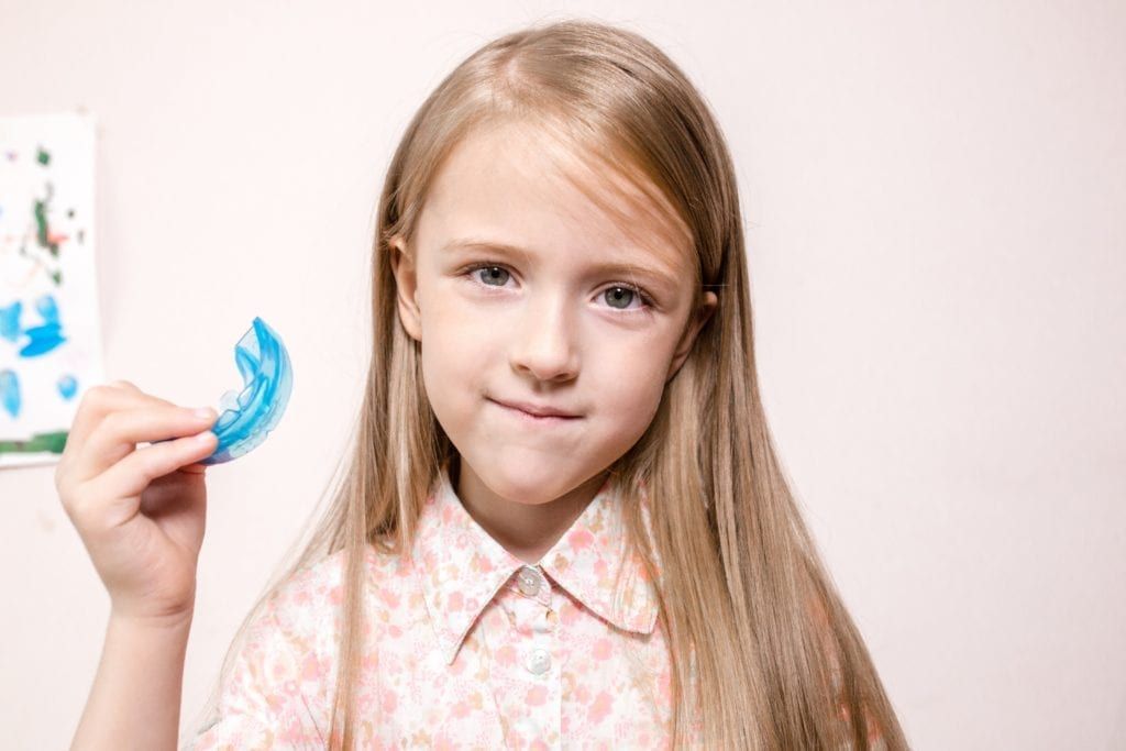 young girl holding a mouthguard
